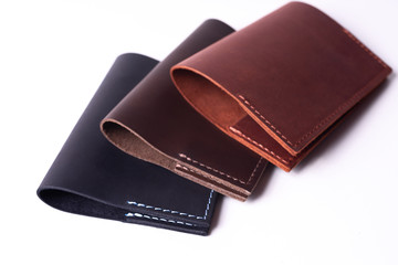 Three handmade leather passport covers isolated on white background. Covers are closed. Closeup view. Covers are dark blue, red and brown.