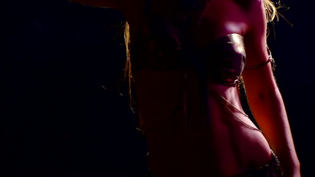 slim athletic body woman dancing Oriental dance in national dress in a dark room in neon light. smooth movements of the hips