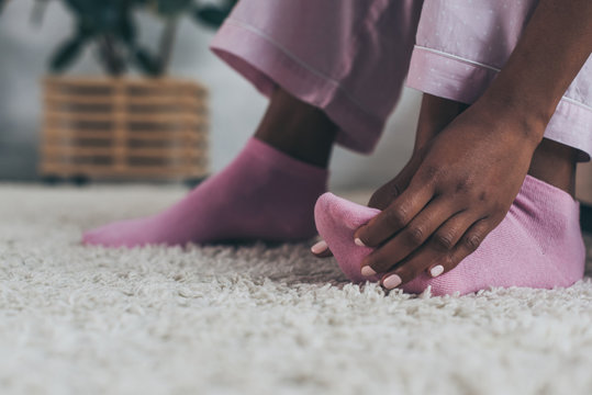 selective focus of african american woman suffering from foot pain in bedroom