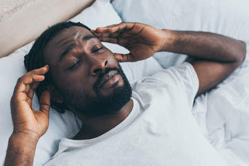 Fototapeta na wymiar handsome african american man suffering from headache with closed eyes