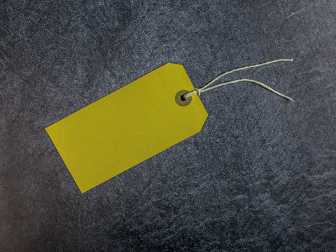 Yellow tag with string on a dark slate background