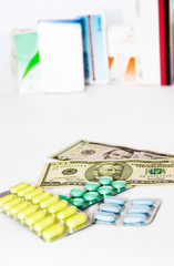 yellow green blue medical pills and american dollars on white background