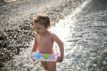 child bathes in the sea, pebble beach, cloudy