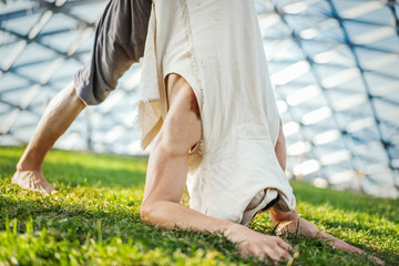Close up of attractive athletic man practicing yoga and warming up outdoors.