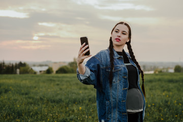 A pregnant woman is taking a picture with her phone. The concept of being pregnant, the future mother enjoys the period of being pregnant. Selfie by phone.