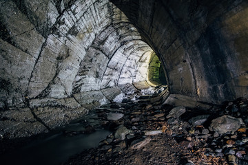 Underground river flowing through large oviform underground turning sewer tunnel