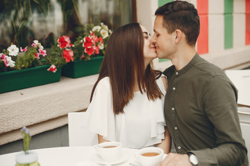 Cute couple in a city. Lady in a white dress. Pair sitting on a cafe