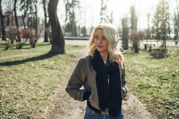 Beautiful Blonde Girl in Green Jacket Listening Music in Headphones