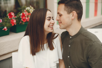 Cute couple in a city. Lady in a white dress. Pair sitting on a cafe