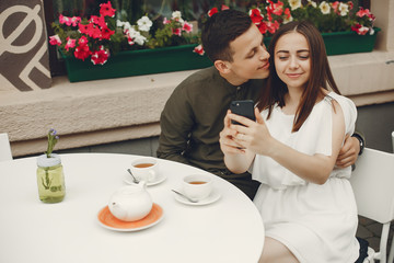 Cute couple in a city. Lady in a white dress. Pair sitting on a cafe