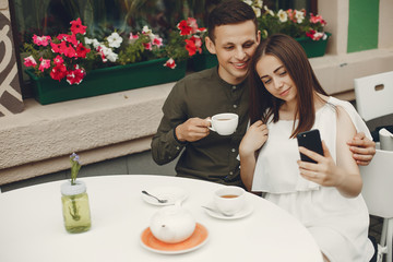 Cute couple in a city. Lady in a white dress. Pair sitting on a cafe