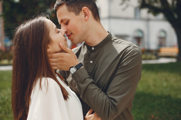 Fototapeta premium Cute couple in a city. Lady in a white dress. Boy in a green shirt