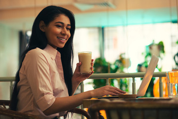 Glad lady looking away while drinking coffee and smiling