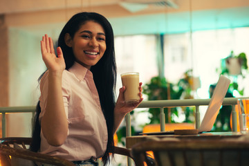 Happy young woman waving her hand and smiling