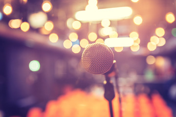 Fototapeta na wymiar Empty event hall: Close up of microphone stand, empty seats in the blurry background