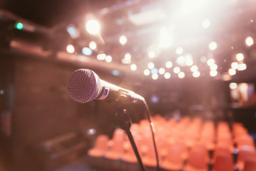 Empty event hall: Close up of microphone stand, empty seats in the blurry background
