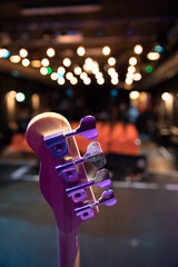 Concert flair: Close up of guitar neck, empty seats and lights in the blurry background