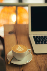 Cup of hot coffee on the plate with teaspoon placed near