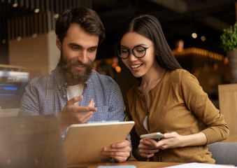 Young smiling multiracial couple sitting together, looking at menu and choosing food in restaurant
