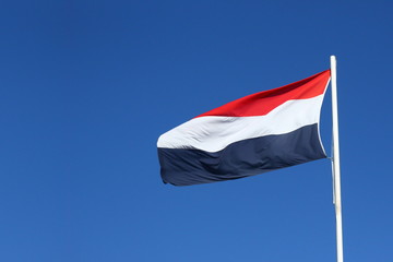 Fototapeta na wymiar Dutch flag waving in the wind on a sunny day with a clear blue sky, with copy space