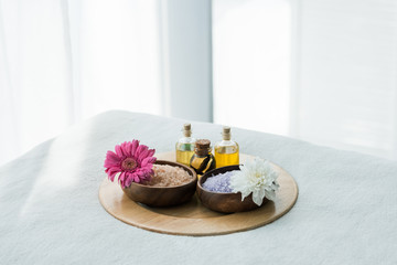 Fototapeta na wymiar tray with bottles of oil, wooden bowls with sea salt and flowers in spa center
