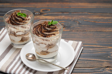 Classic tiramisu dessert in a glass on wooden background