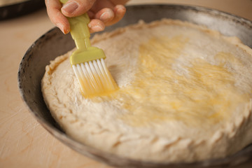Woman lubricates an pie by egg. Top view