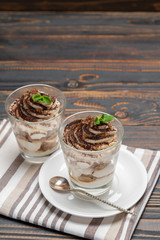 Classic tiramisu dessert in a glass on wooden background