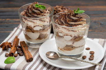 Classic tiramisu dessert in a glass on wooden background