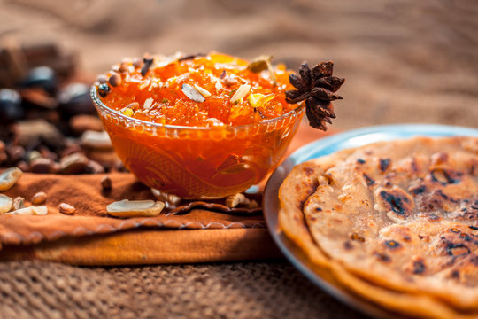 Famous mango preservation i.e. Murba or Murabba in a glass bowl on jute bags surface along with dry fruits and spices with it.Horizontal shot with background blurred.