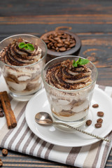 Classic tiramisu dessert in a glass on wooden background