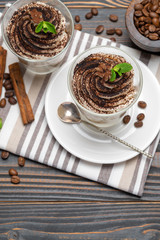 Classic tiramisu dessert in a glass on wooden background