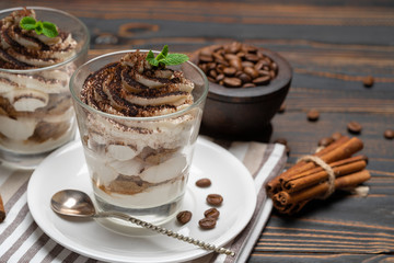Classic tiramisu dessert in a glass on wooden background