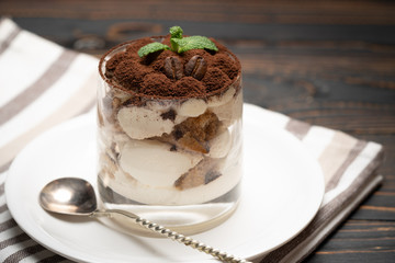 Classic tiramisu dessert in a glass on wooden background