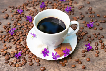 white cup of coffee on a wooden table, chocolate, sugar and coffee beans,