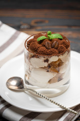 Classic tiramisu dessert in a glass on wooden background