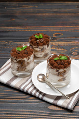 Classic tiramisu dessert in a glass on wooden background