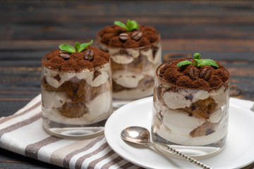 Classic tiramisu dessert in a glass on wooden background