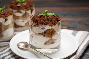 Classic tiramisu dessert in a glass on wooden background