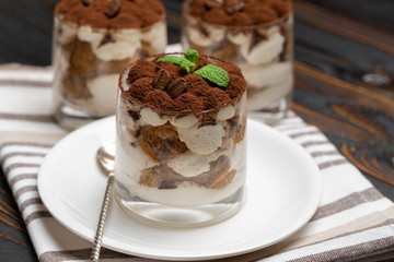 Classic tiramisu dessert in a glass on wooden background