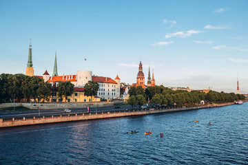 Obraz premium Panoramic view of the Old Town from the cable-stayed bridge to the Daugava embankment at sunset. Riga, Latvia. Riga Castle with the Riga Cathedral in front of. St. Peter's Church in the background.