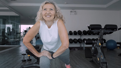 Elderly woman makes squattings in the gym. Elderly woman Senior woman makes a sport exercises in the gym. 