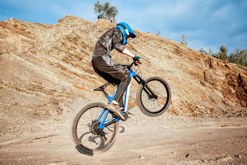 Professional well-equipped cyclist riding bicycle on the rocky mountains. Concept of a freeride and off road cycling