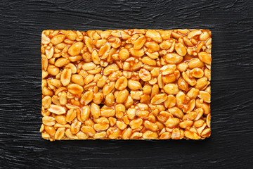 Golden boletus kozinaki from roasted peanut beans energy bars. Black textural background, top view