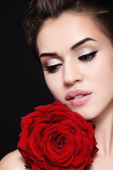 Fototapeta na wymiar Portrait of young beautiful woman with winged eye makeup and red rose