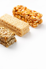 Grain granola bar with peanuts, sesame and seeds in a row on a white background. Top view Three assorted bars, isolate