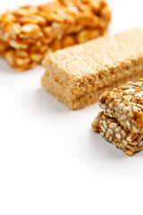 Grain granola bar with peanuts, sesame and seeds in a row on a white background. Top view Three assorted bars, isolate