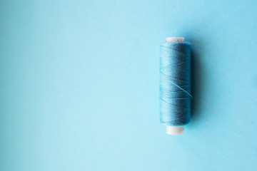 Multicolored thread coils on pink blue background. Sewing supplies and accessories for needlework,...