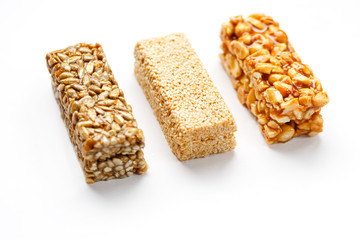 Grain granola bar with peanuts, sesame and seeds in a row on a white background. Top view Three assorted bars, isolate