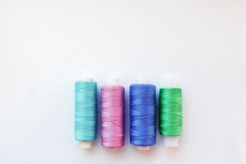 Multicolored thread coils on pink blue background. Sewing supplies and accessories for needlework, stitching, embroidery. space for text. flat lay, top view 